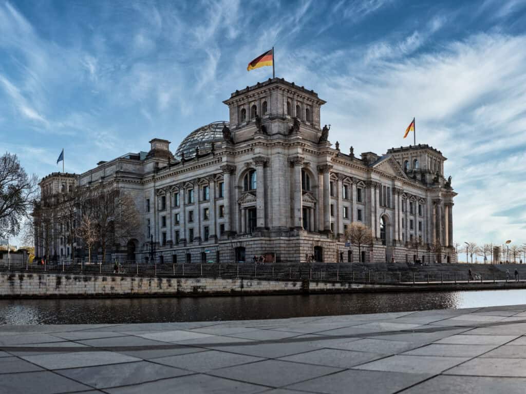 Reichstagsgebäude in Berlin mit Deutschlandflaggen, politische Diskussion im öffentlichen Dienst.