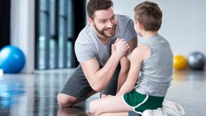 Mann und Kind beim Armwrestling, positive Interaktion im sozialen Arbeitsumfeld.