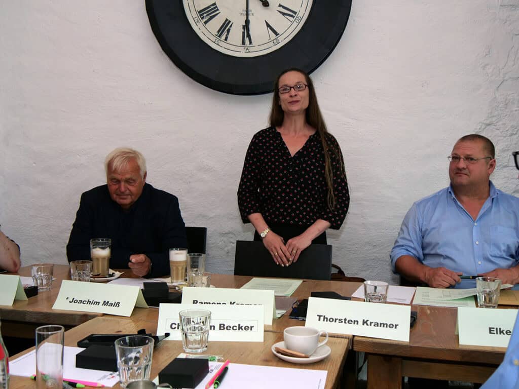 Frauen- und Männergruppe bei einer Diskussion im Konferenzraum, sitzend an einem langen Tisch mit Ge.