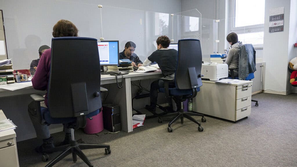 Teamarbeit in einem modernen Büro mit mehreren Personen an Computern.