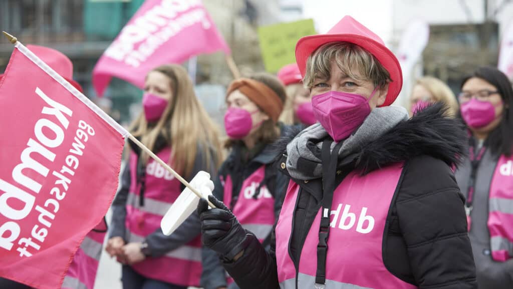 Teilnehmerinnen bei Warnstreik in Flensburg mit pinken Masken und Plakaten.