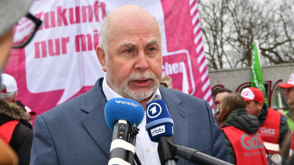 Mann spricht bei Demonstration gegen Angebotsmogelpackung, umweltbewusstes Engagement.