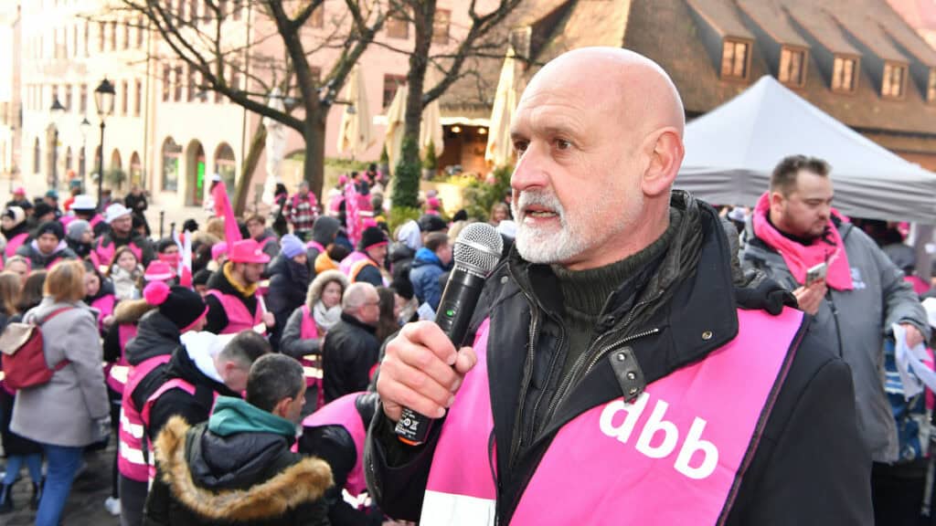 Mann bei Warnstreik in Bayern während Einkommensrunde, spricht in Mikrofon.