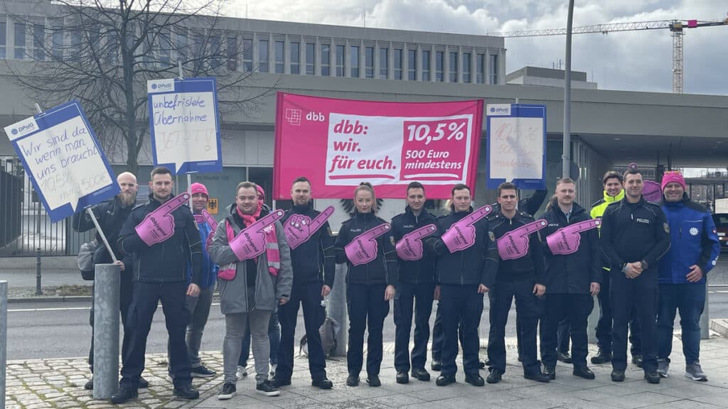 Gruppe von Demonstranten mit pinken Plakaten bei Protestaktion in Deutschland.