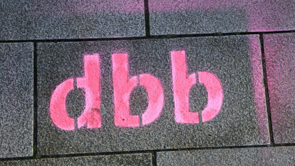 Graffiti "dbb" auf Gehweg in Dresden während Protestaktion.