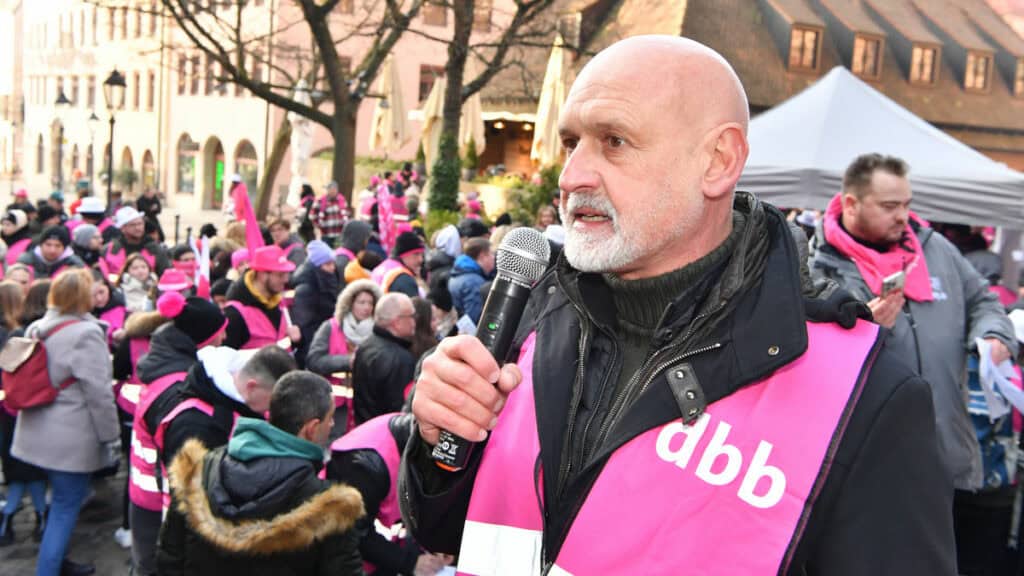 Mann spricht bei Demonstration für zukunftssichere Arbeitsbedingungen.