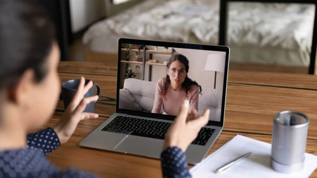 Frau bei mobiler Arbeit im Homeoffice, Videokonferenz am Laptop.