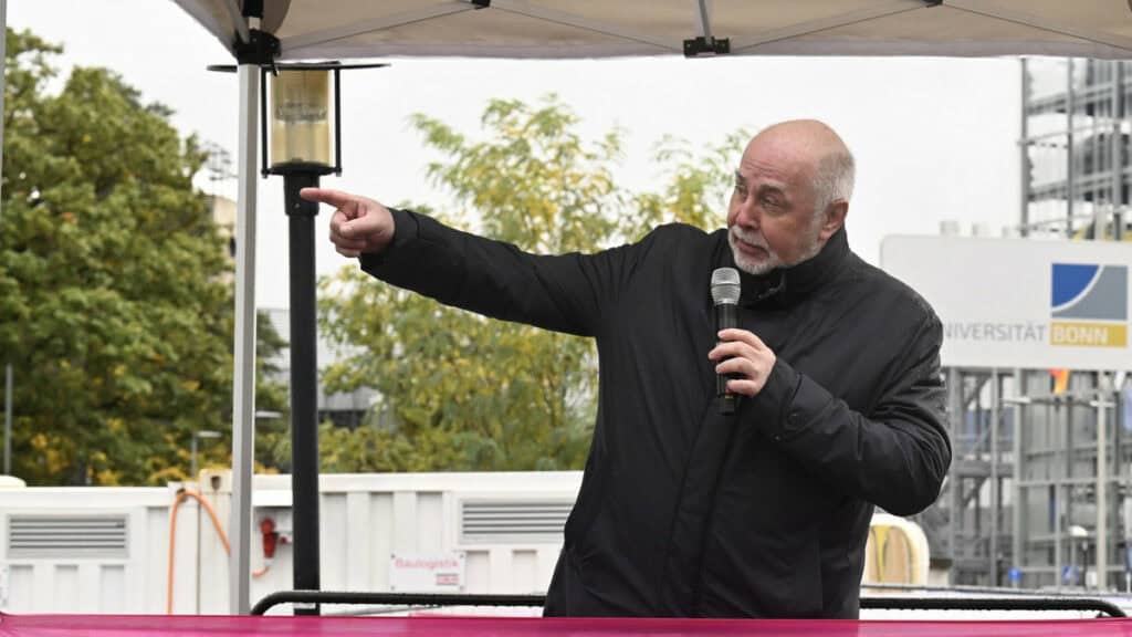 Politiker Silberbach spricht bei einer Veranstaltung vor Publikum, zeigt auf etwas im Hintergrund.