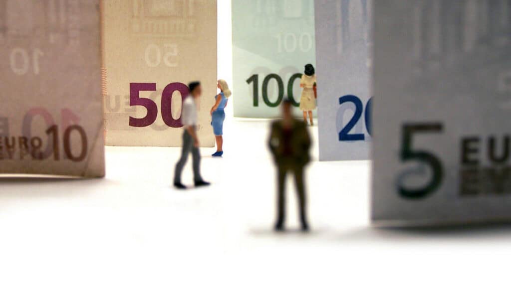 Miniaturansicht von Euro-Banknoten und Miniaturfiguren vor Geldscheinen.