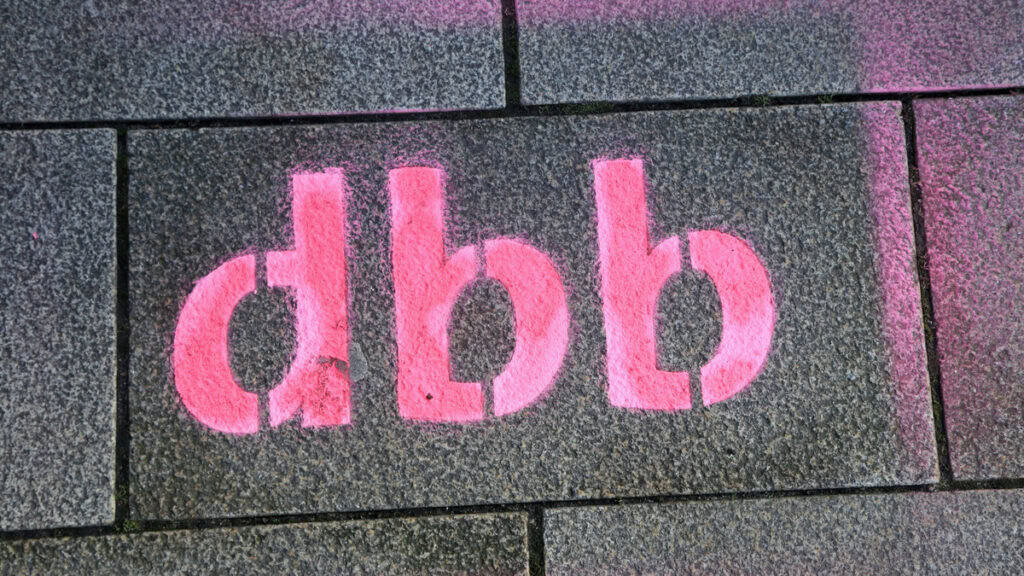 Grafik des Logos "dbb" auf Pflasterstein, symbolisiert moderne staatliche Rahmenbedingungen.