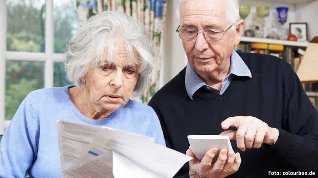 Älteres Paar prüft Renteninformationen auf einem Tablet und Smartphone.