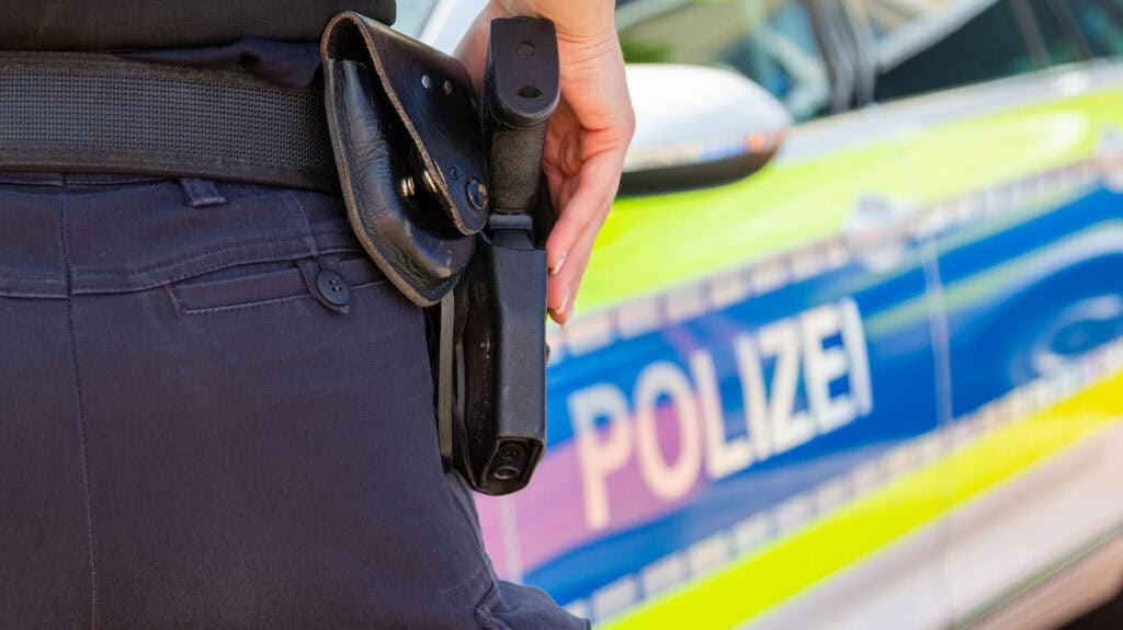 Polizeibeamter mit Waffe bei Einsatz im Zusammenhang mit Gewalt.
