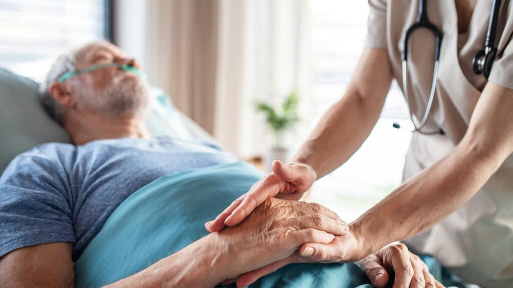 Arzt hält Hand eines Patienten während der Krankenhausreform-Debatte.