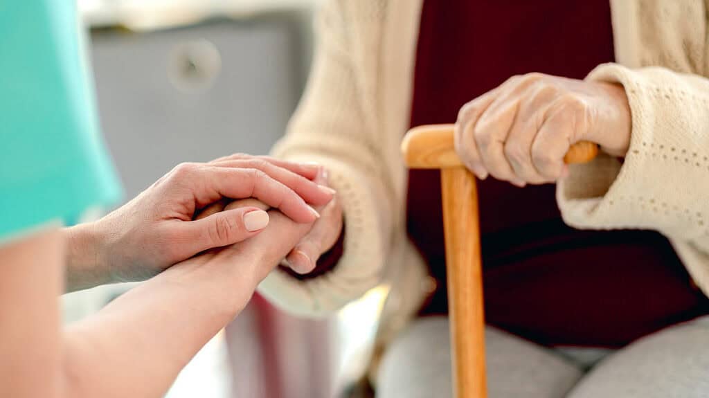 Hände halten sich im Pflegeheim, symbolisiert Unterstützung im Alter.