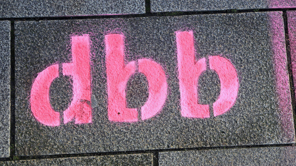 Digitales Rathaus-Symbol in Pink auf Steinmauer.