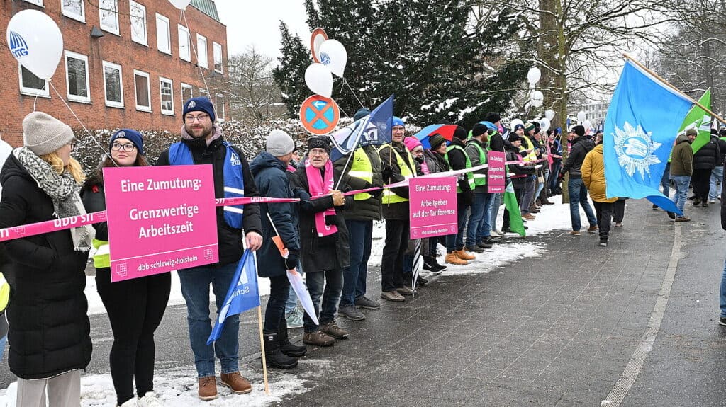 Demonstration von Beschäftigten im öffentlichen Dienst mit Plakaten und Flaggen im Winter.