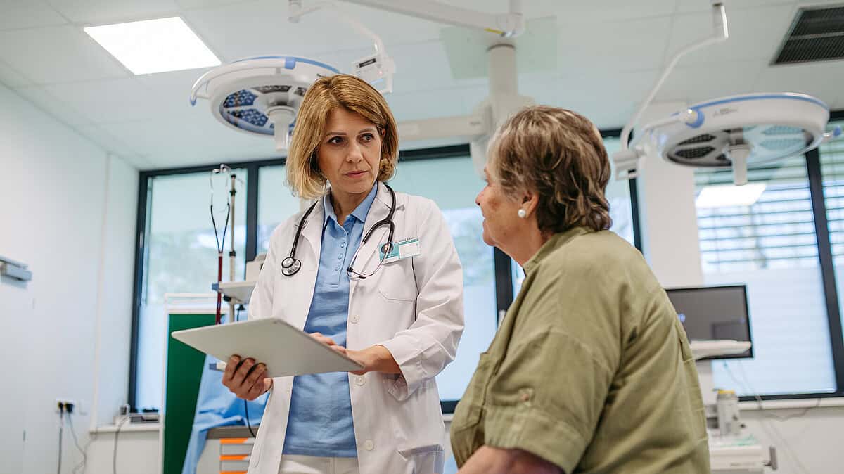 Ärztin spricht mit Patientin im Krankenhaus über Gesundheitsreformen.