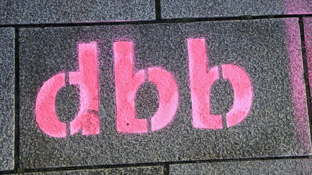 Pink bemalte Schablone auf Gehweg, symbolisiert kreative Straßenkunst.