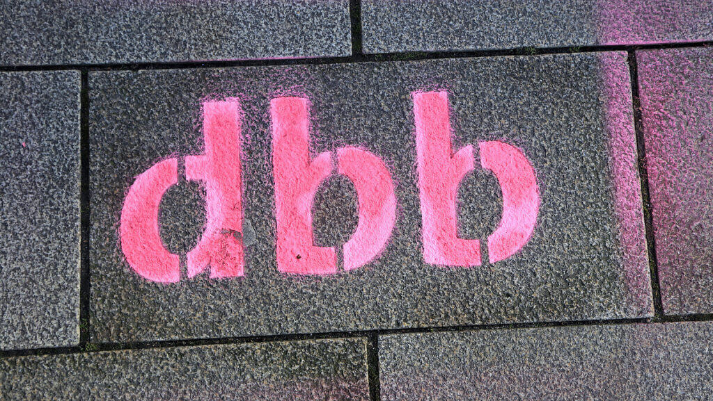 Graffiti "dbb" auf Gehwegplatten, Symbol für öffentlichen Dienst.