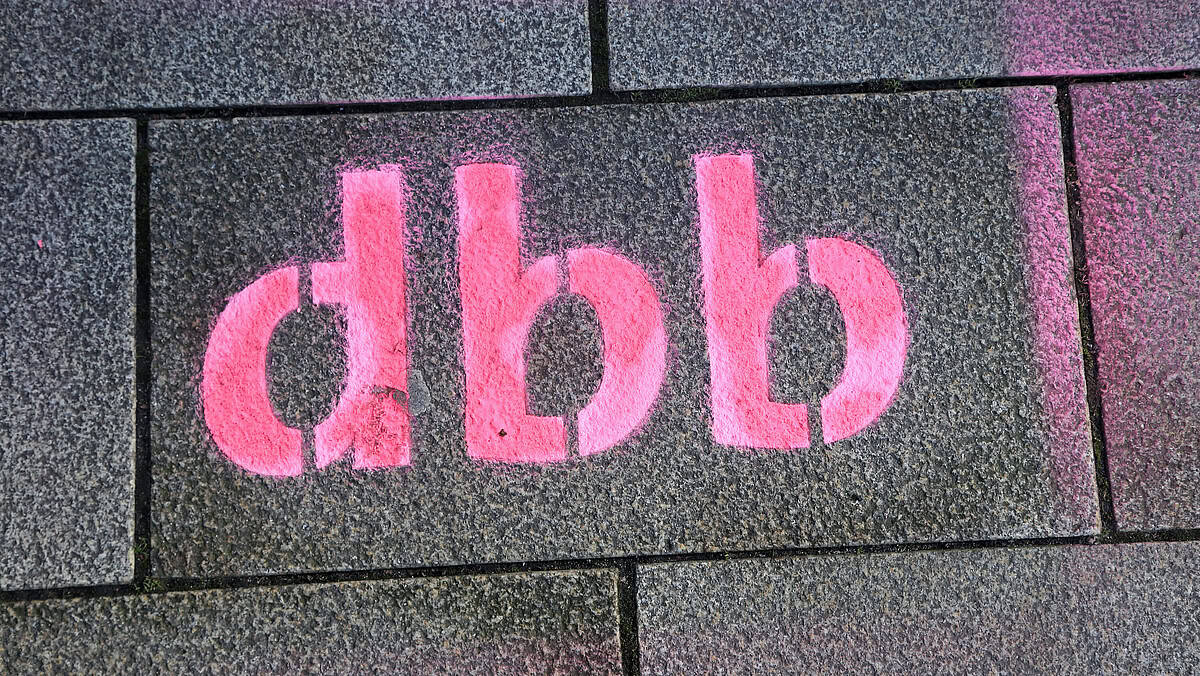 Graffiti "dbb" auf Gehwegplatten, Symbol für öffentlichen Dienst.