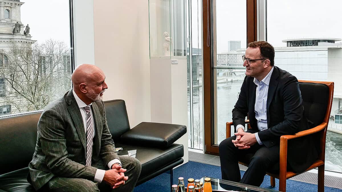 Zwei Männer im Gespräch in einem modernen Büro mit Blick auf die Stadt.