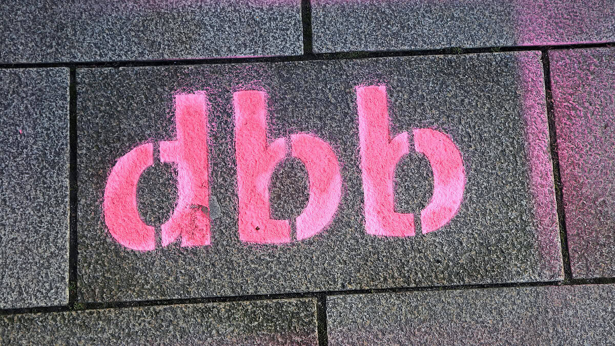 Graffiti mit pinkem "dbb" auf Steinmauer, politische Botschaft.